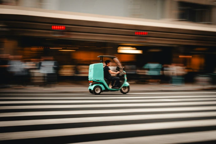 A scooter delivering food on a crosswalk.